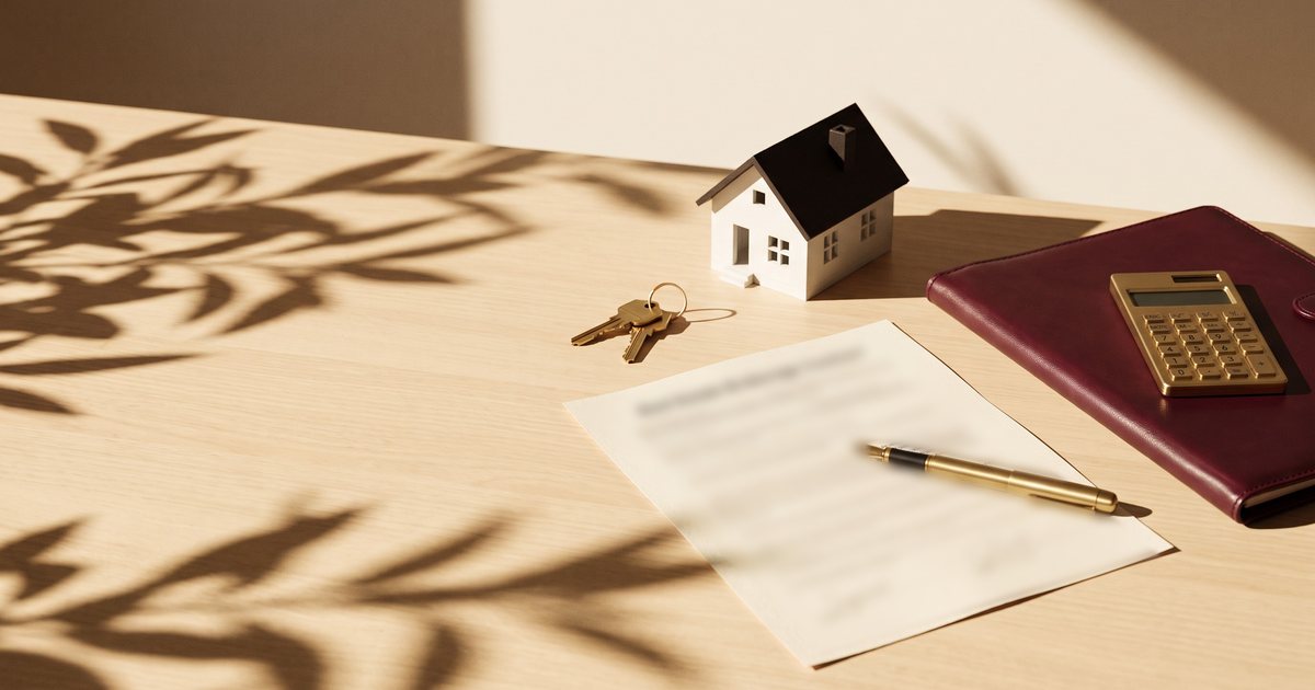 Contrato de corretagem imobiliária com caneta, chaves e miniatura de casa sobre a mesa